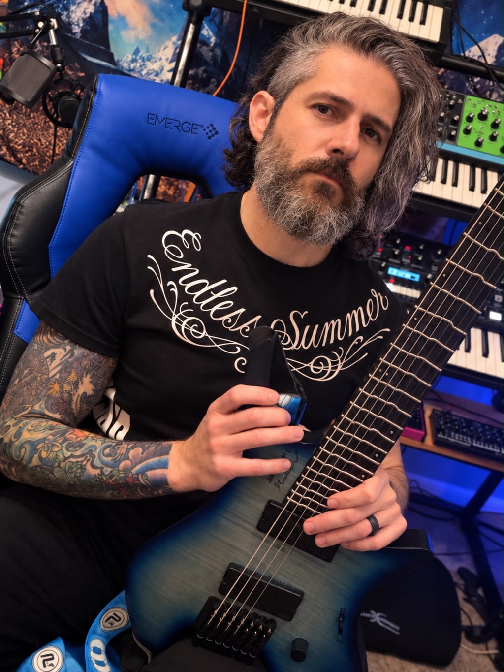 Enzo Ferrera holding an extended-range electric guitar in his studio